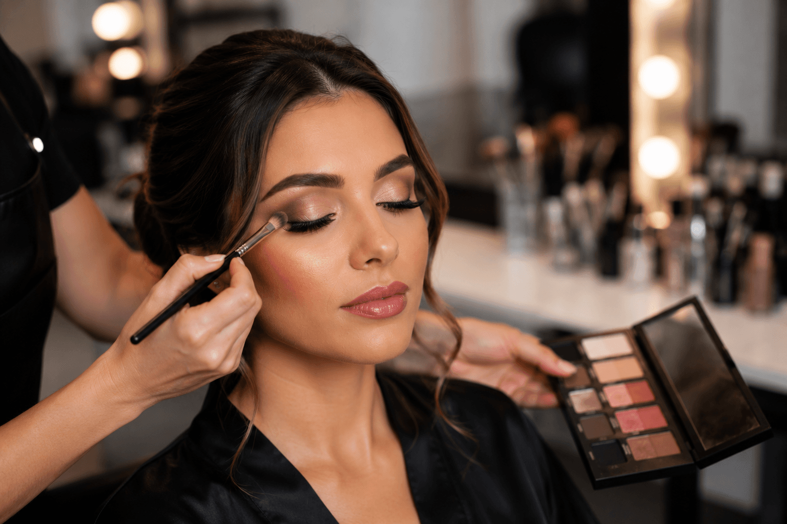 Maquiadora finalizando a maquiagem de uma cliente